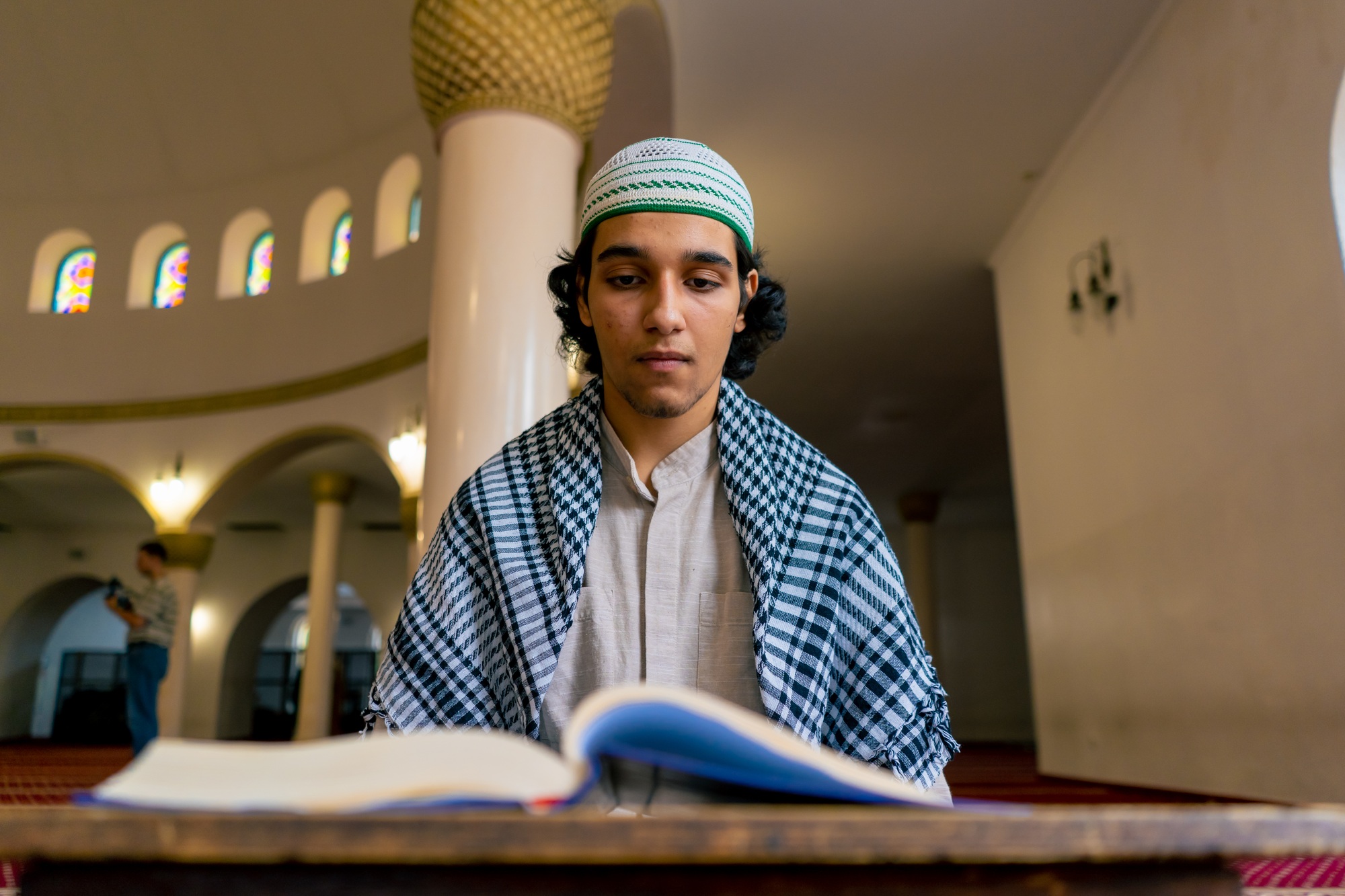 A Muslim man sits in silence on the carpet in holy mosque prays reads the Koran and turns to Allah
