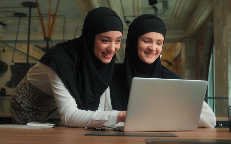 Two Arabian muslim islamic women hijab girls ladies businesswomen advice software laptop consulting