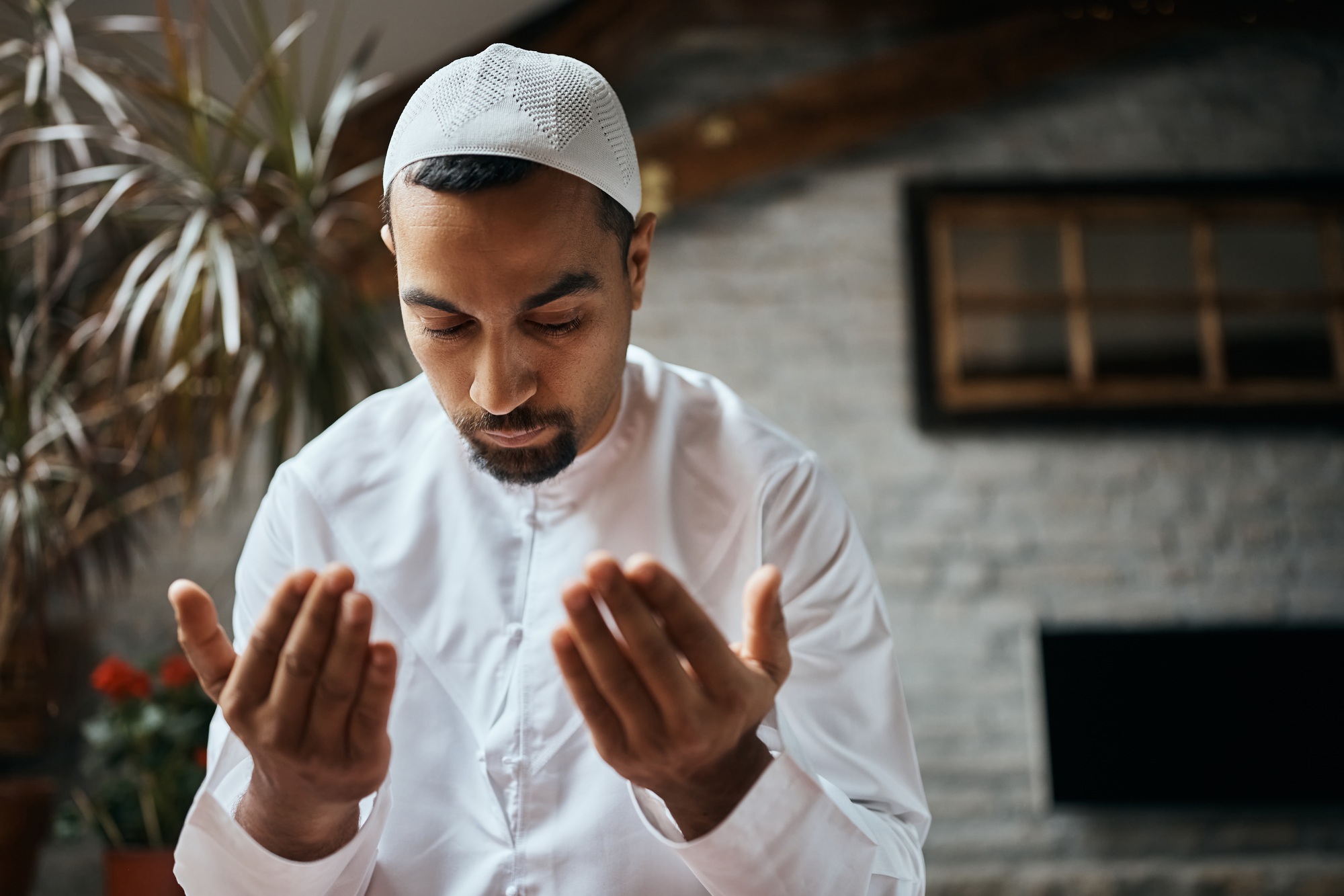 Mid adult man of Islam faith praying at home.