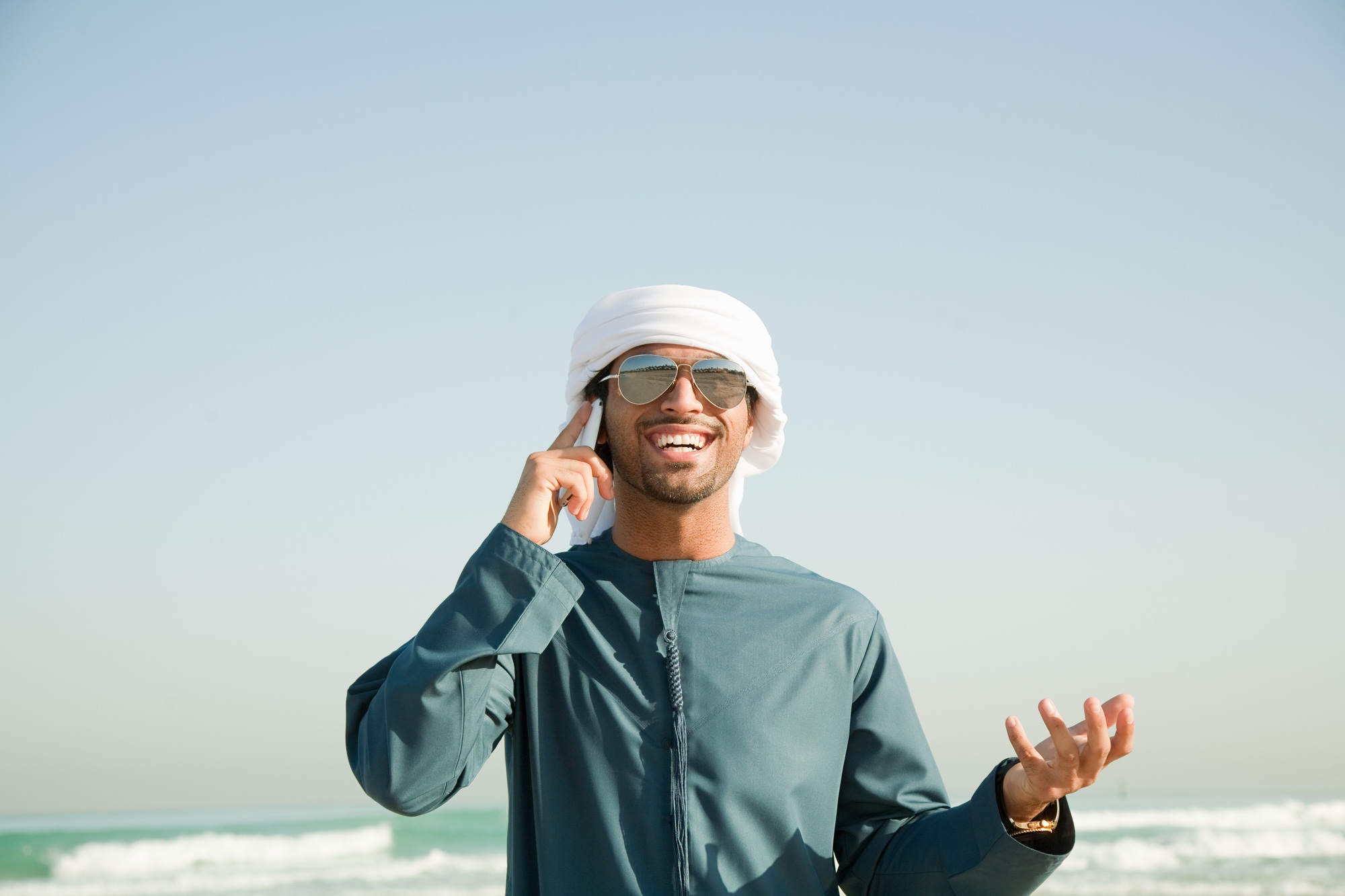 Middle Eastern man using mobile phone on the beach