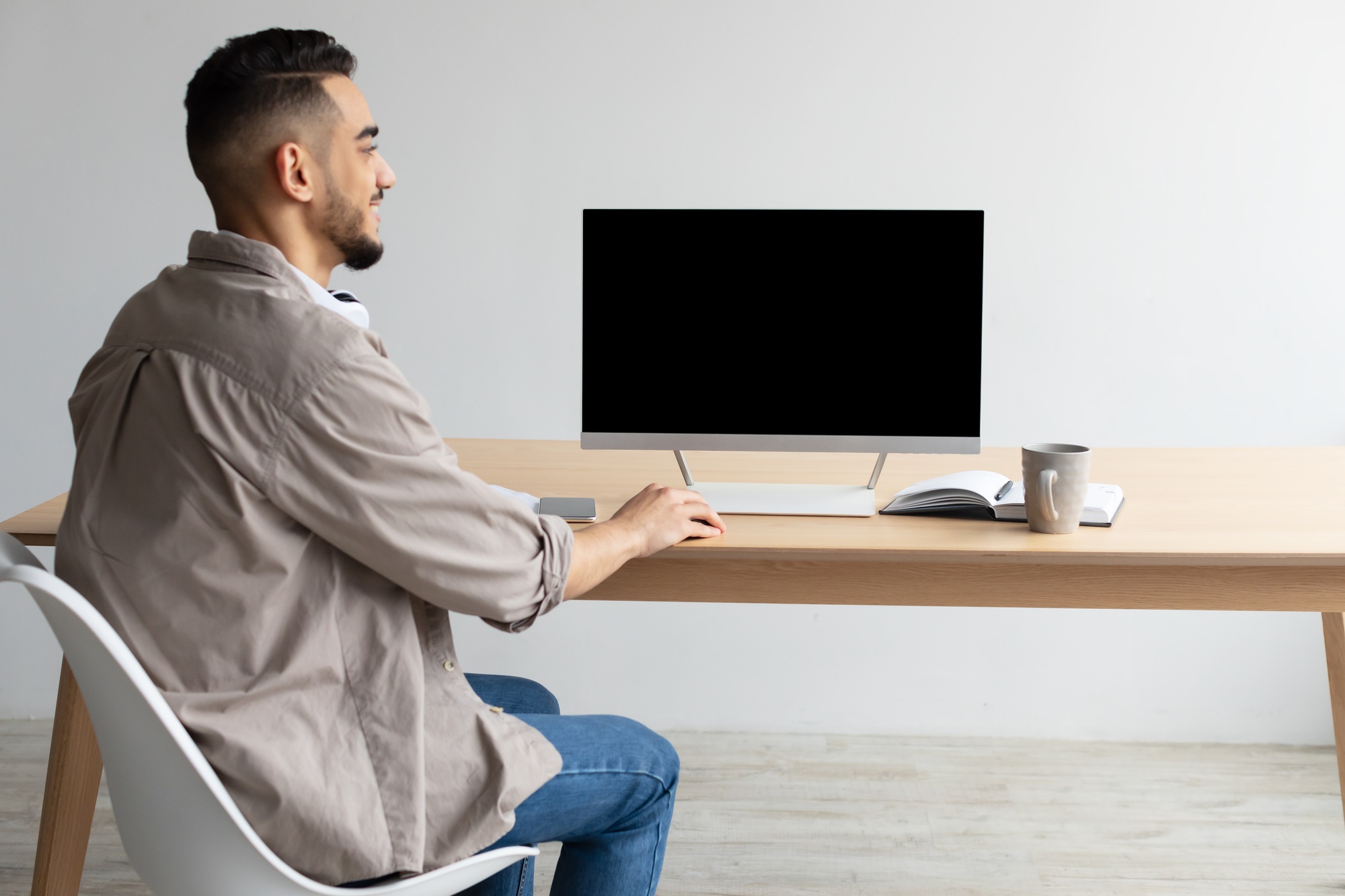 Arab man looking at blank empty computer monitor