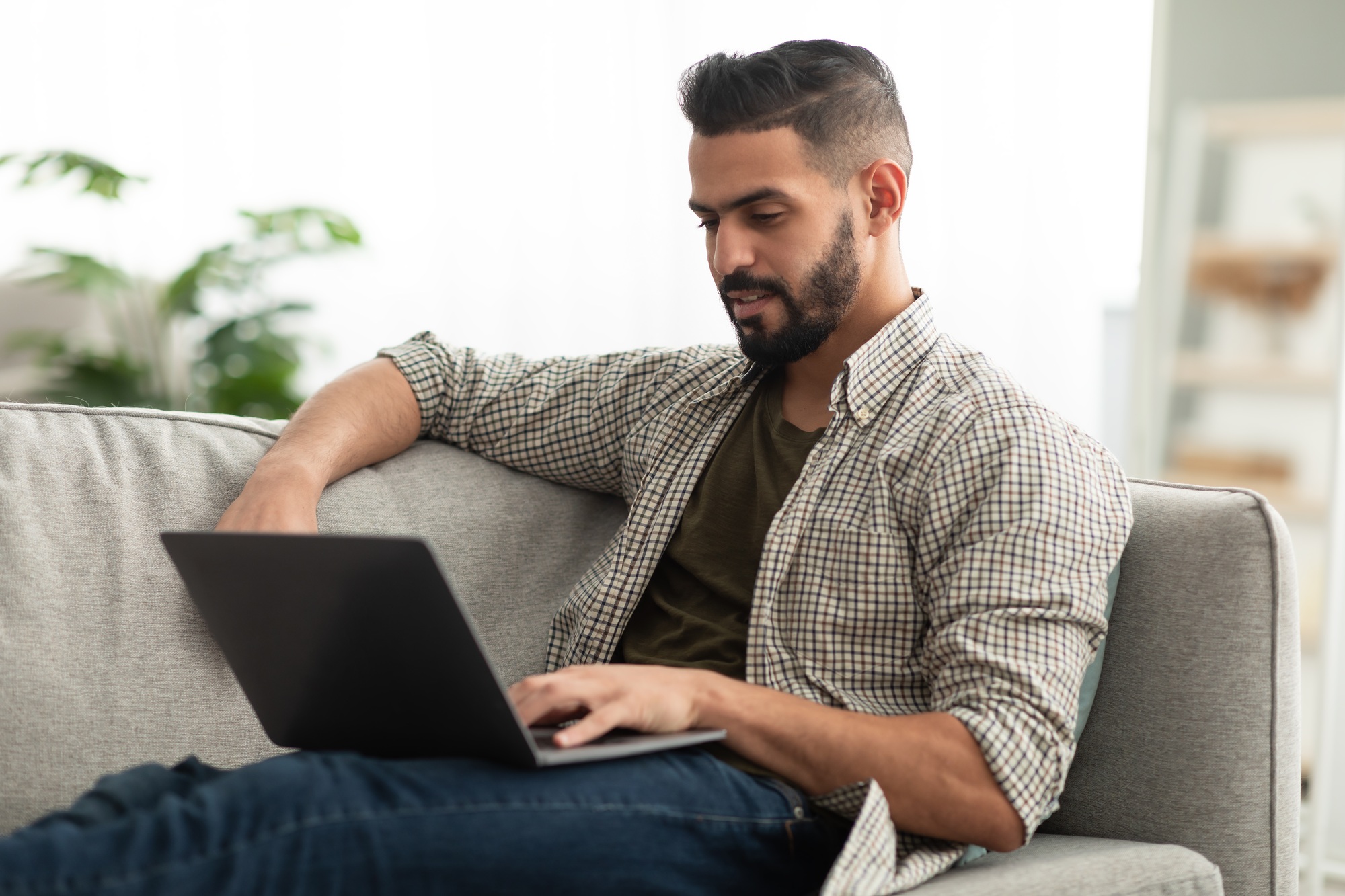 Millennial Arab male freelancer working online on laptop at home office