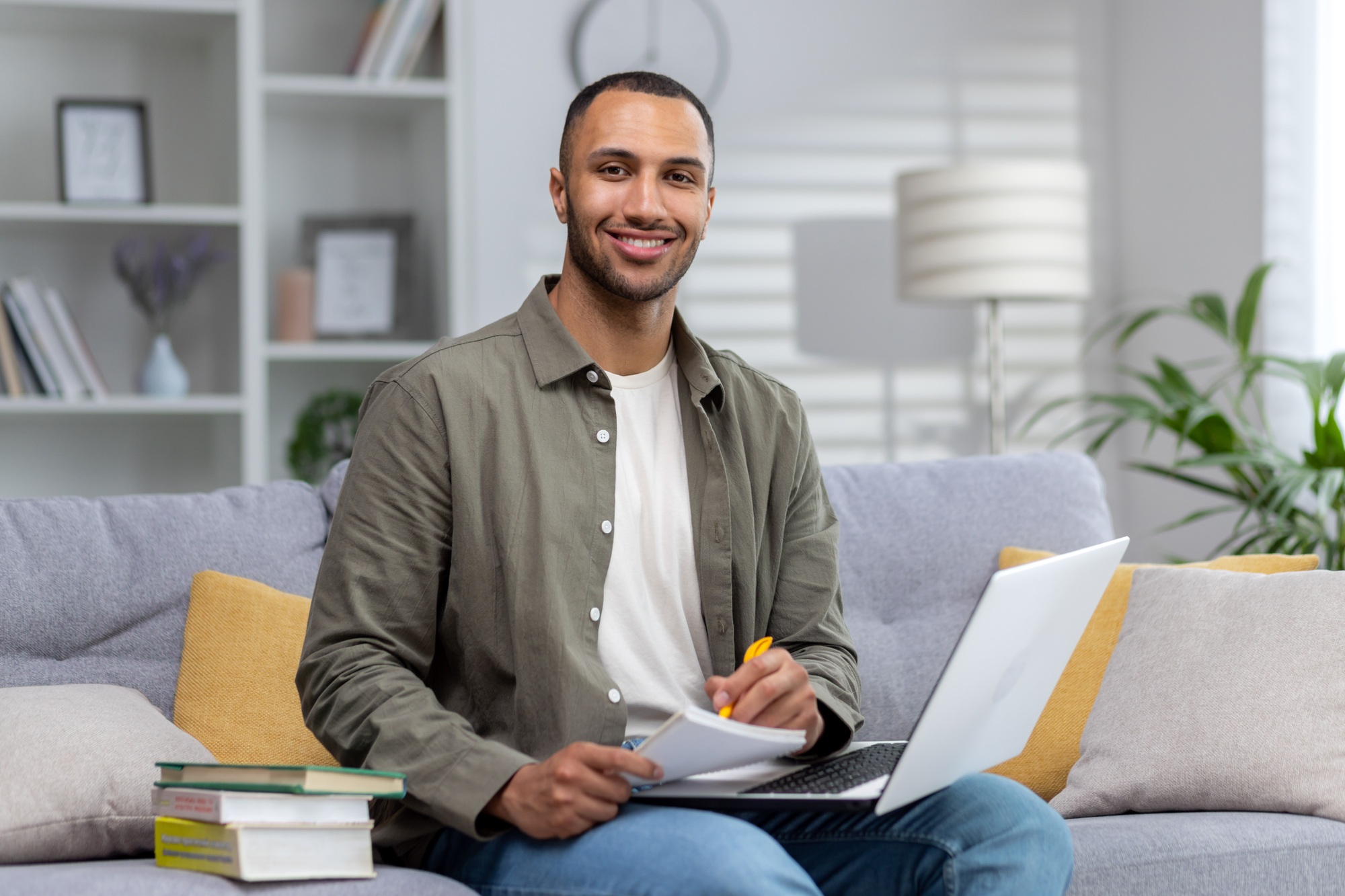 Portrait of a young Latin American teacher smiling at the camera while sitting on the couch at home