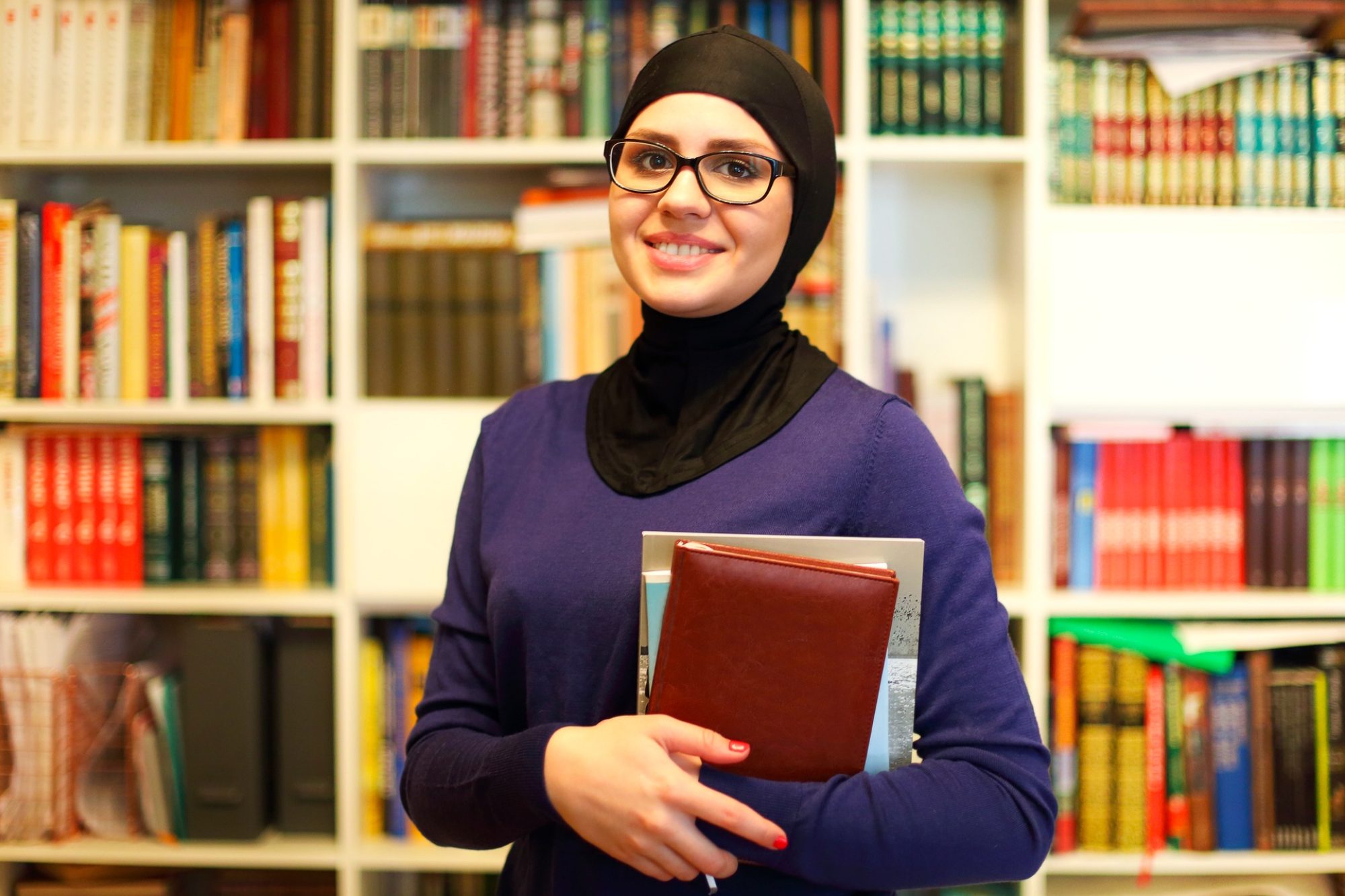 Smiling Islamic student with books in library