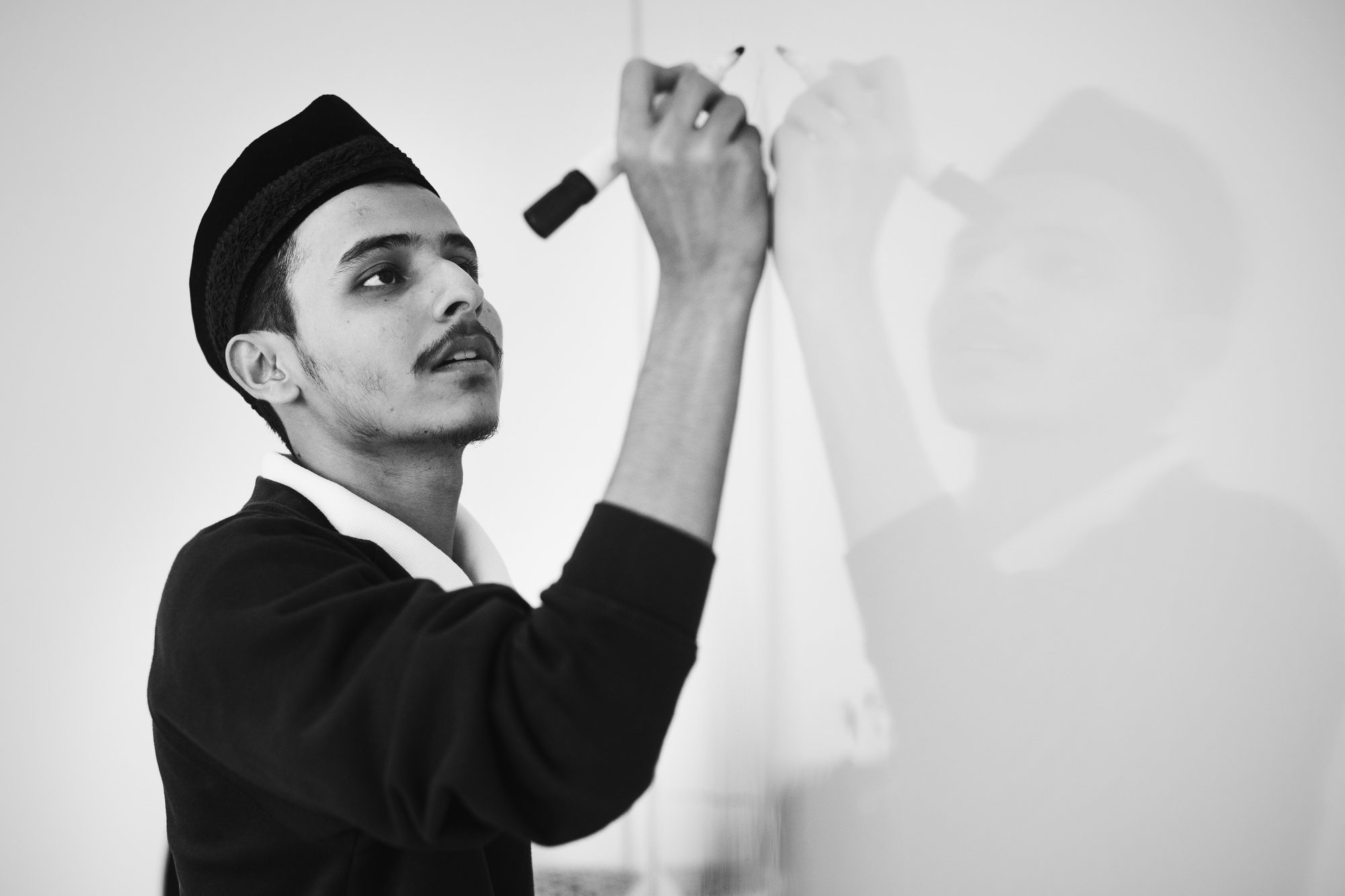 Young muslim man is writing a white board