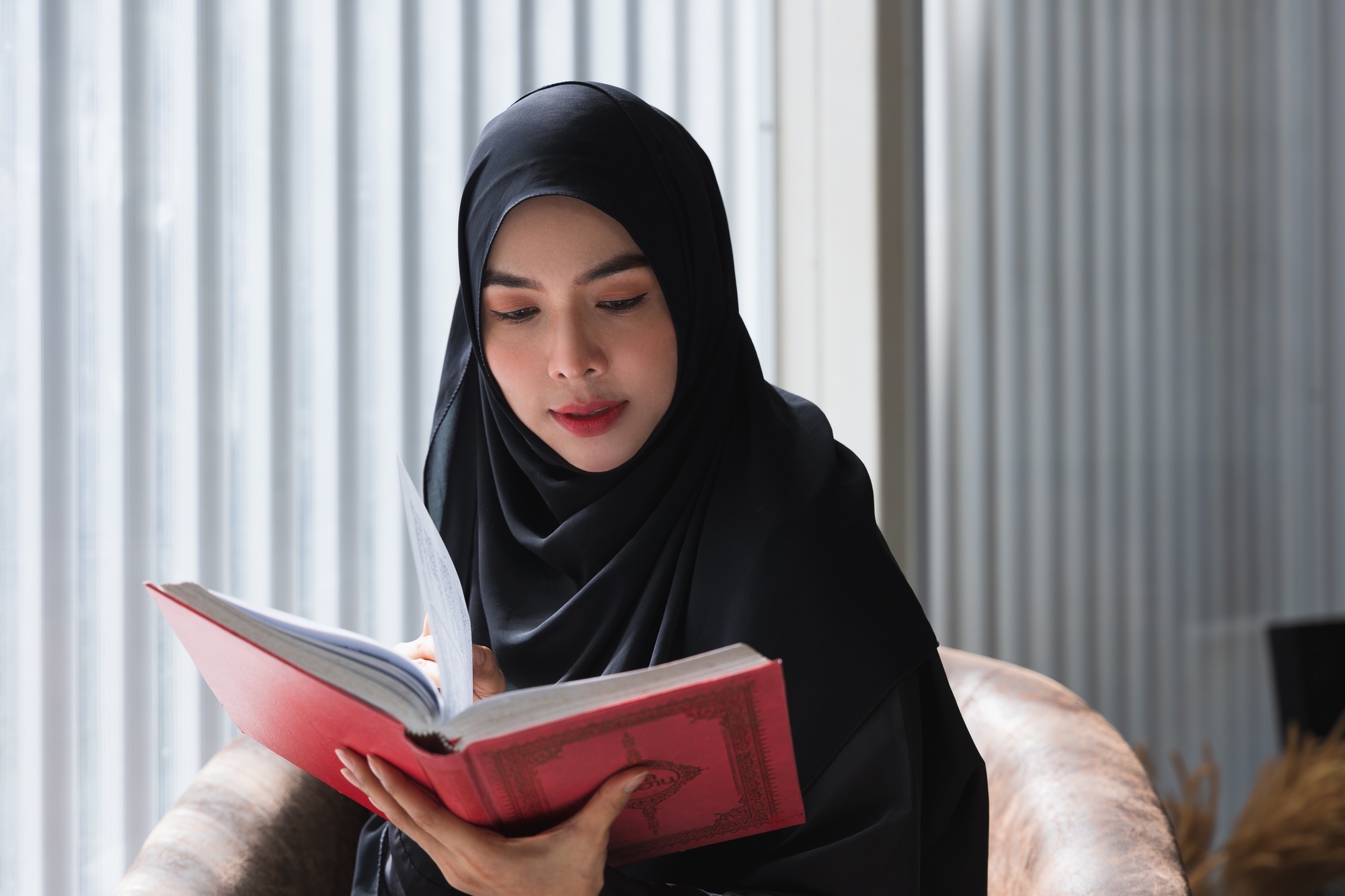 Young Asian woman reading the Islamic Quran or Koran
