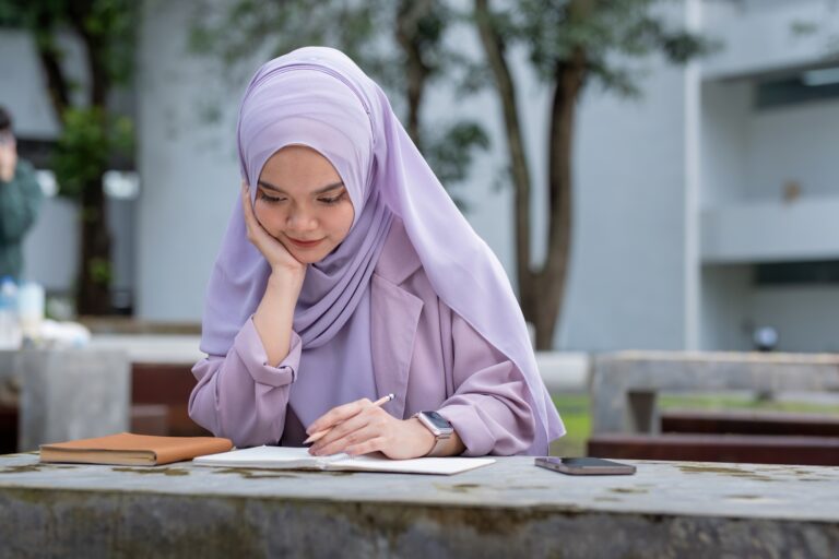 Beautiful Muslim college student girl taking note at university