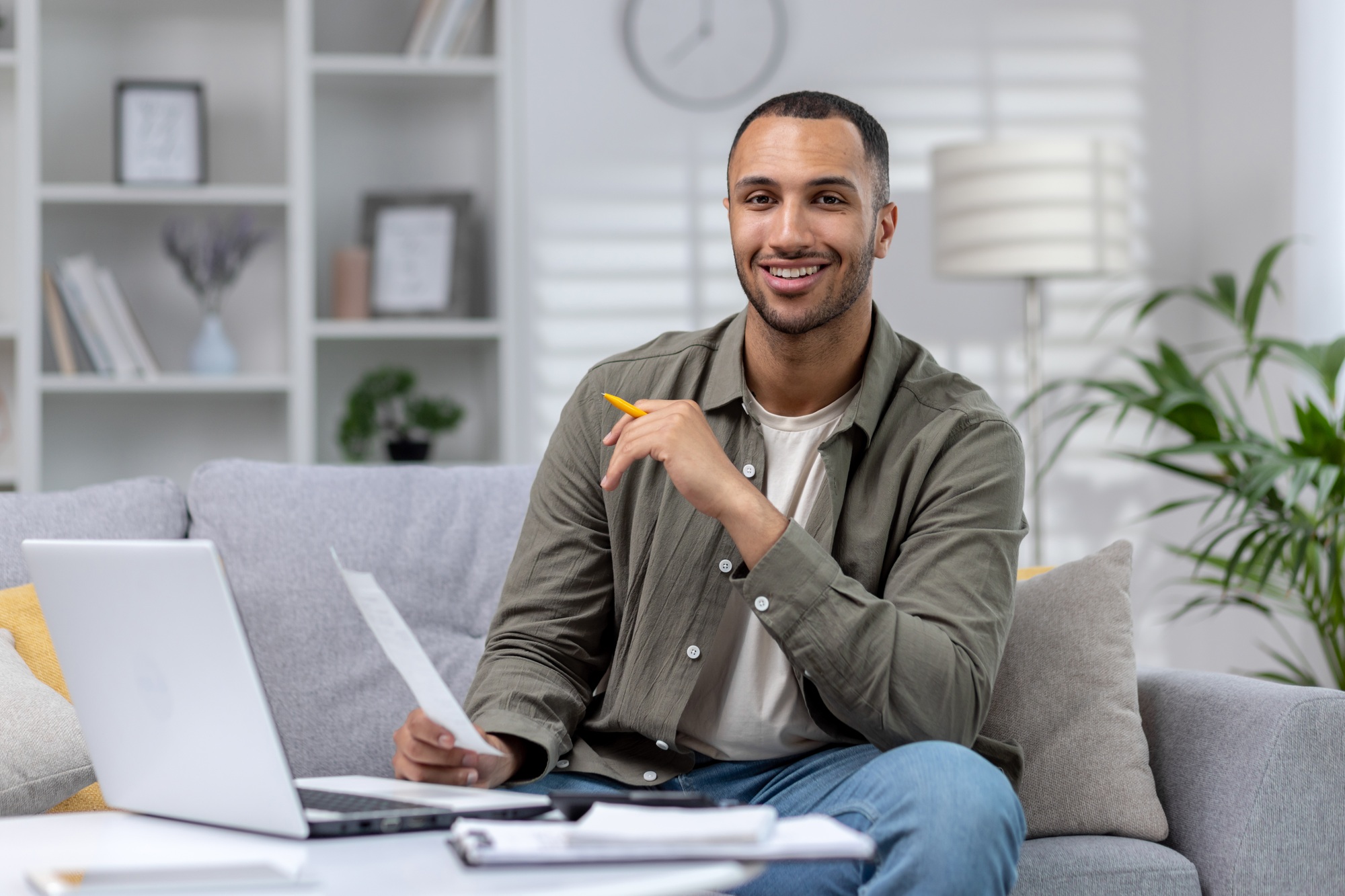portrait-of-a-young-muslim-male-student-studying-remotely-at-home-using-a-laptop-and-smiling-at-the
