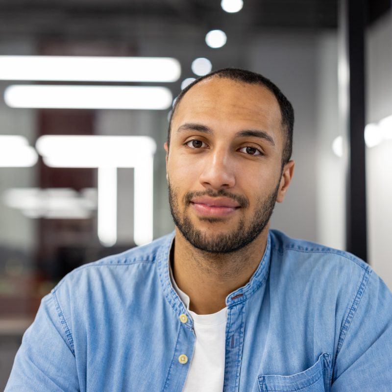 close-up-portrait-of-a-young-muslim-man-sitting-in-a-modern-office-in-a-denim-shirt-and-looking