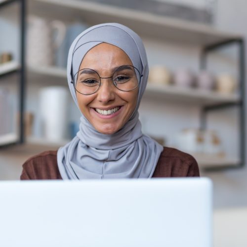 close-up-photo-of-young-beautiful-arab-woman-in-hijab-and-glasses-working-at-home-sitting-in-kitchen