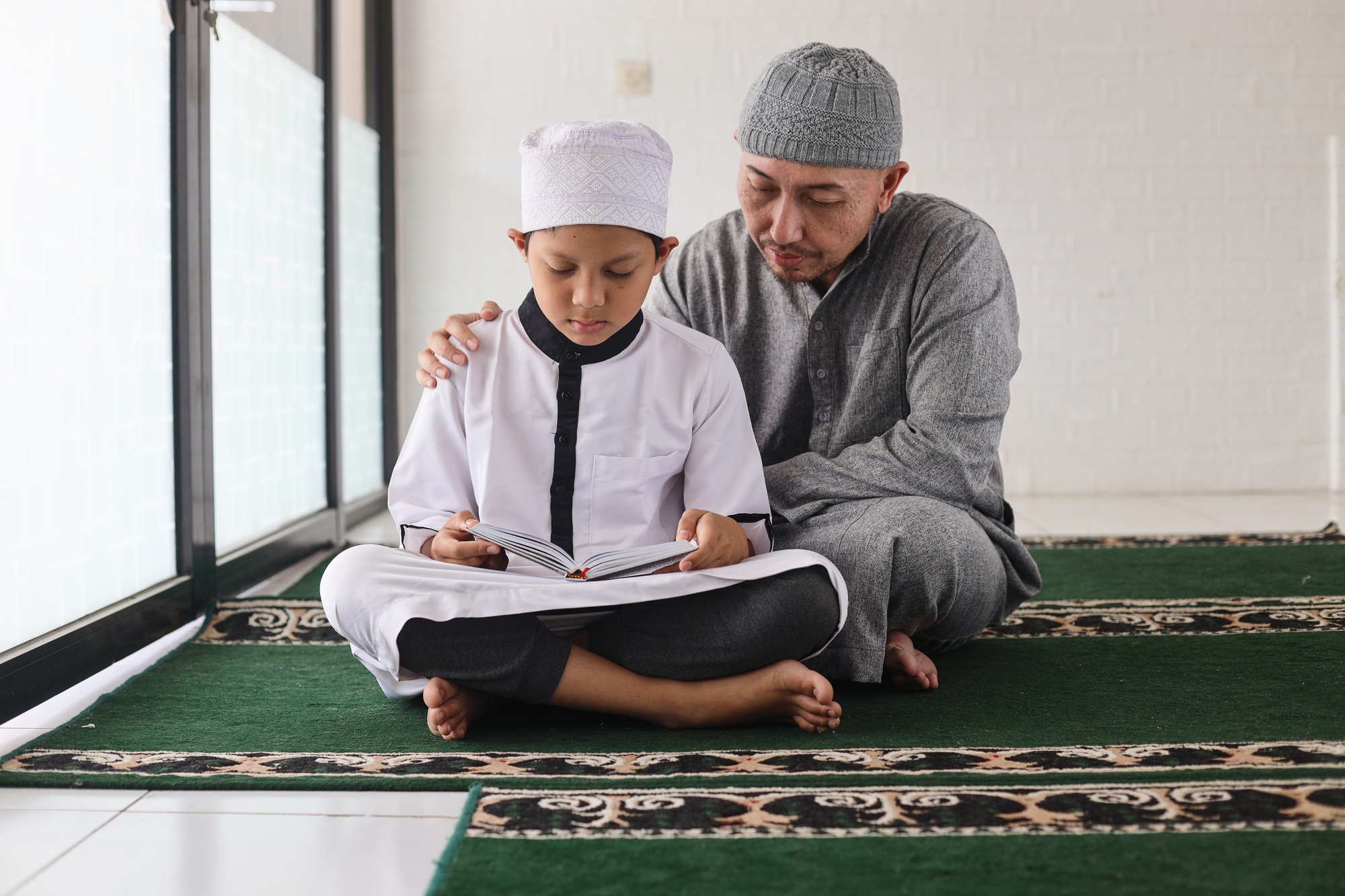 Father teaching son reading Al Qur'an