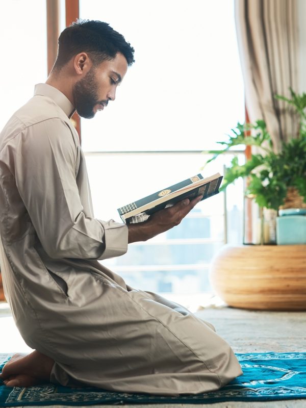 this-is-how-i-fight-my-battles-shot-of-a-young-muslim-man-reading-in-the-lounge-at-home-