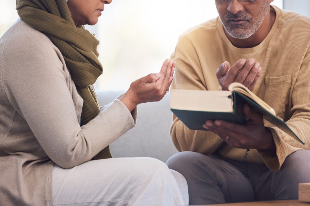 Worship, prayer and Muslim couple with a quran, reading and studying spiritual faith in their house
