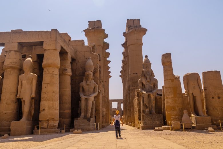 Woman tourist with a hat visiting the Egyptian Temple of Luxor and its beautiful columns